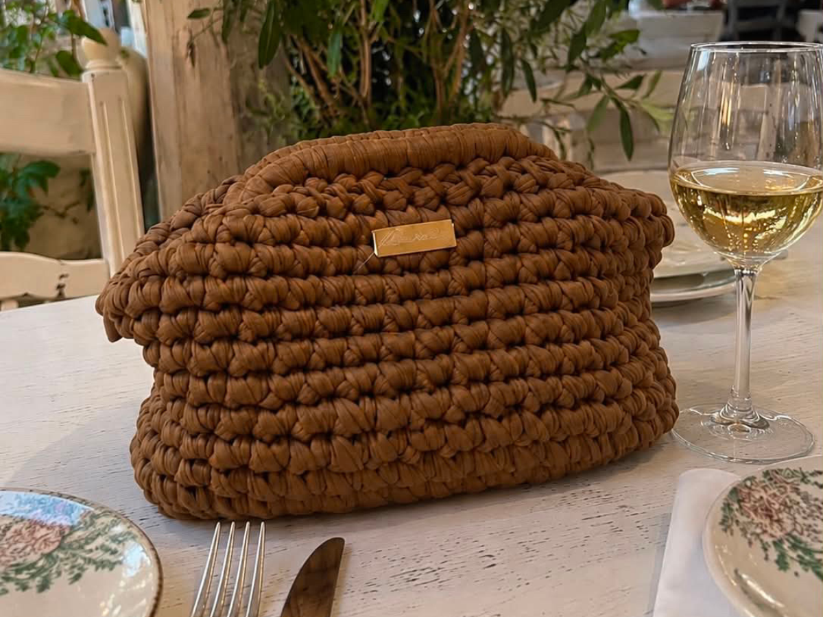 Clutch Françoise - Sac crochet caramel Laurette Créations posée sur une table de restaurant en bord de mer