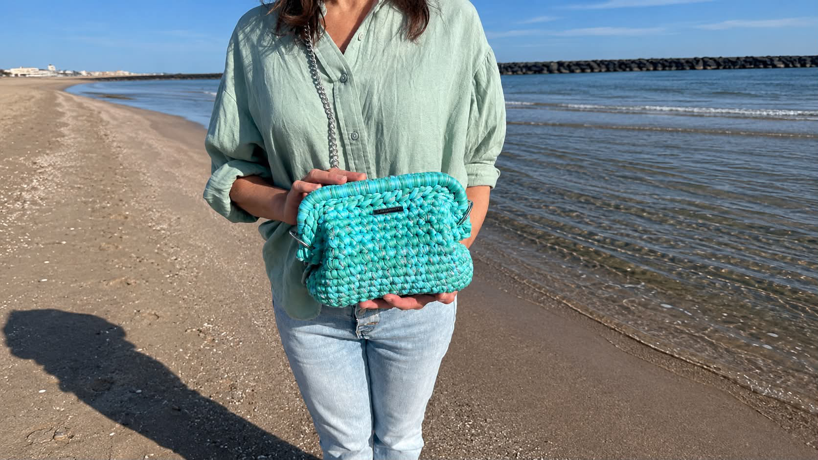 Femme sur la plage tenant le Clutch Françoise en taille unique - Laurette Creations
