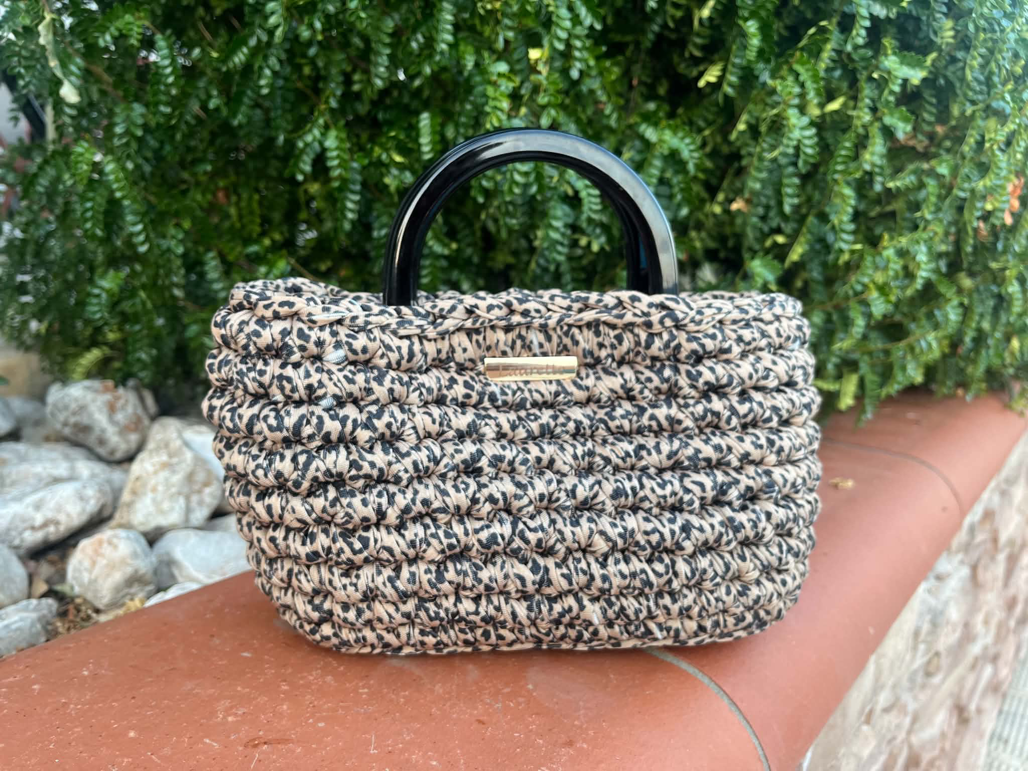 Sac Laurette léopard avec une hanse rigide sur un muret de jardin