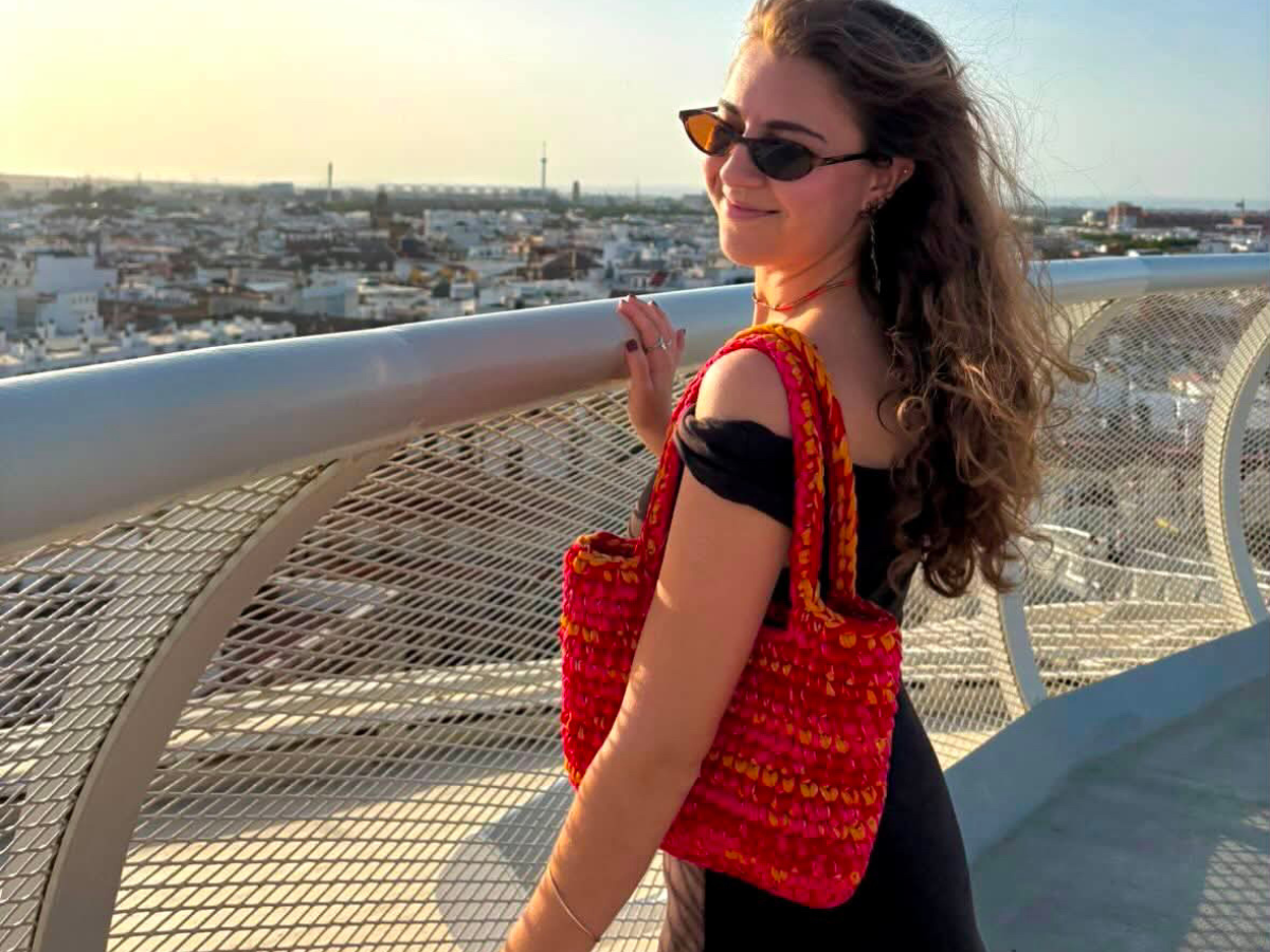 Femme portant le Tote Bag Marcelle en crochet rouge et orange à l'épaule, création faite main Laurette Créations